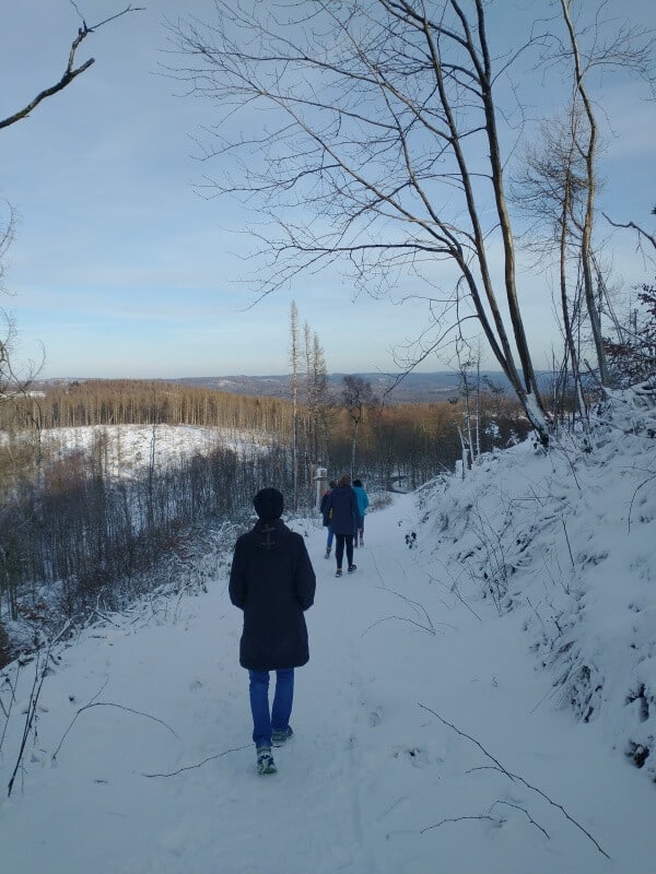 mehrere Personen wandern durch die verschneite Landschaft auf dem Ravensberg