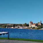 Süßer See - Blick über den See auf das Seeburger Schloss, vorn links im Bild ein kleiner Steg mit anlegenden Booten, der vom Ufer aus über das Wasser ragt